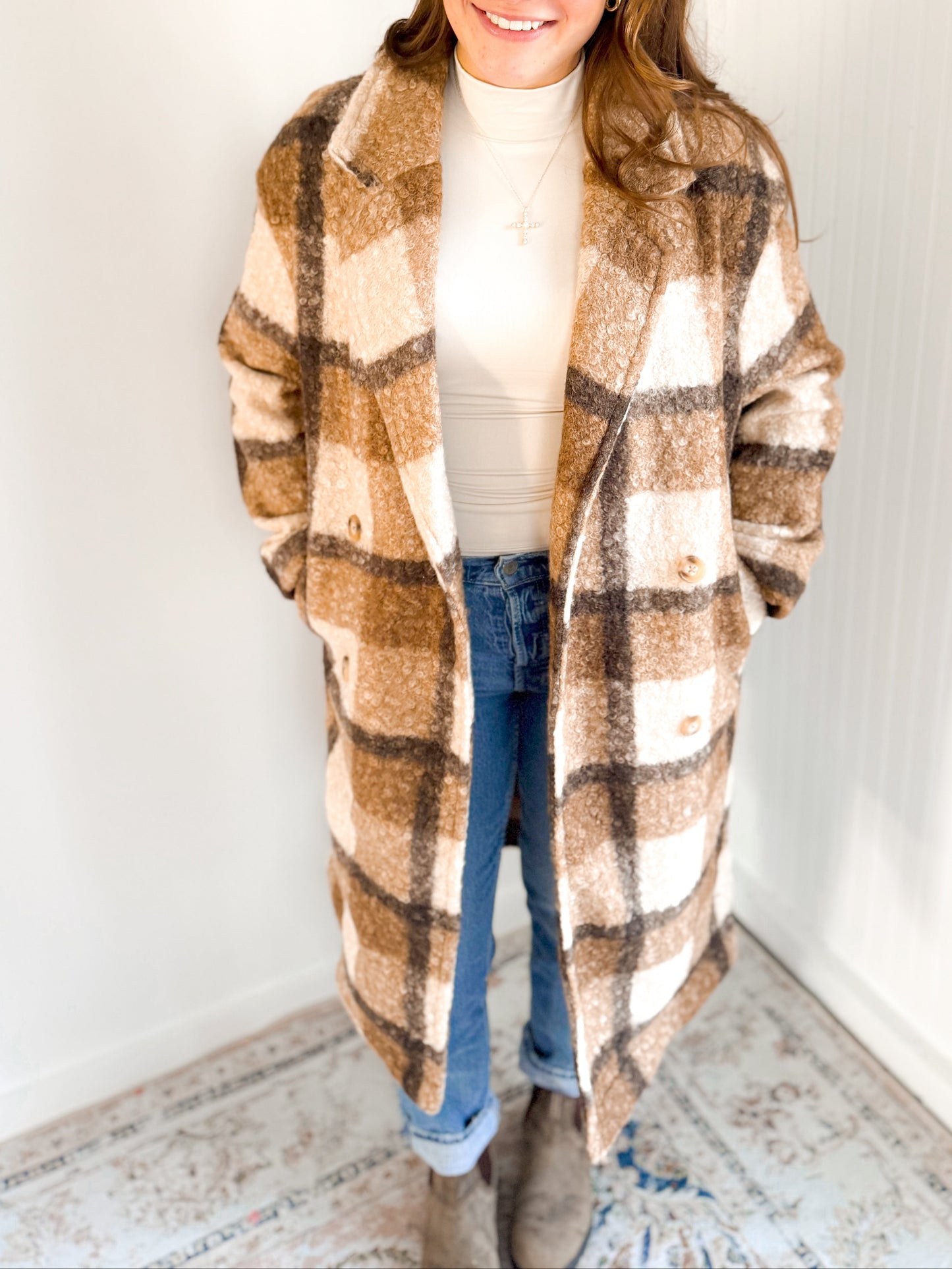 Person wearing a plaid coat with a white wall background
