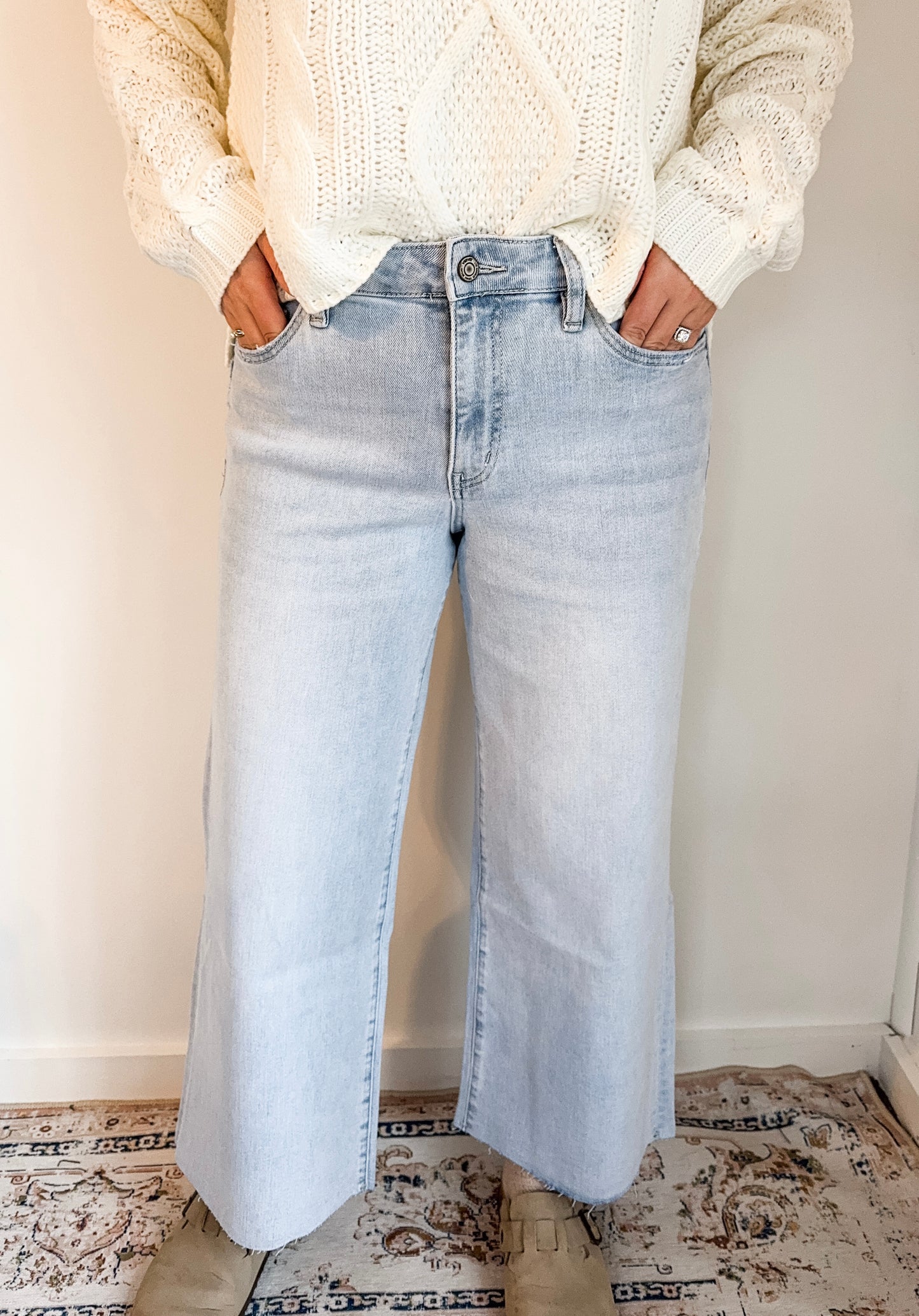 Person wearing light blue jeans and a cream sweater indoors.