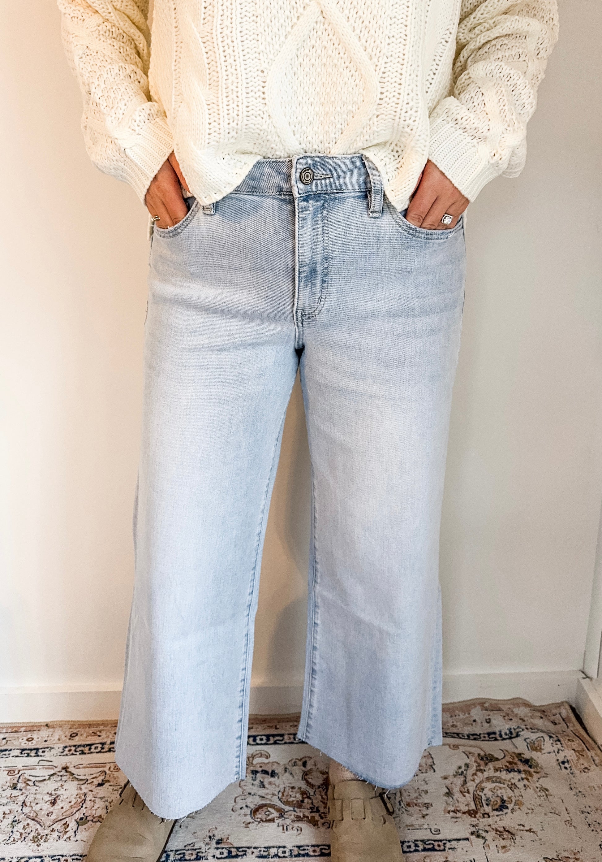 Person wearing light blue jeans and a cream sweater indoors.