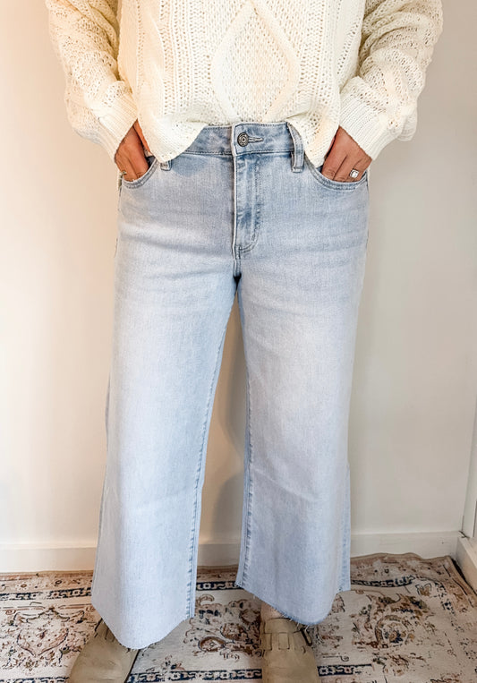 Person wearing light blue jeans and a cream sweater indoors.