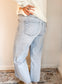 Light blue jeans worn by a person against a neutral wall.