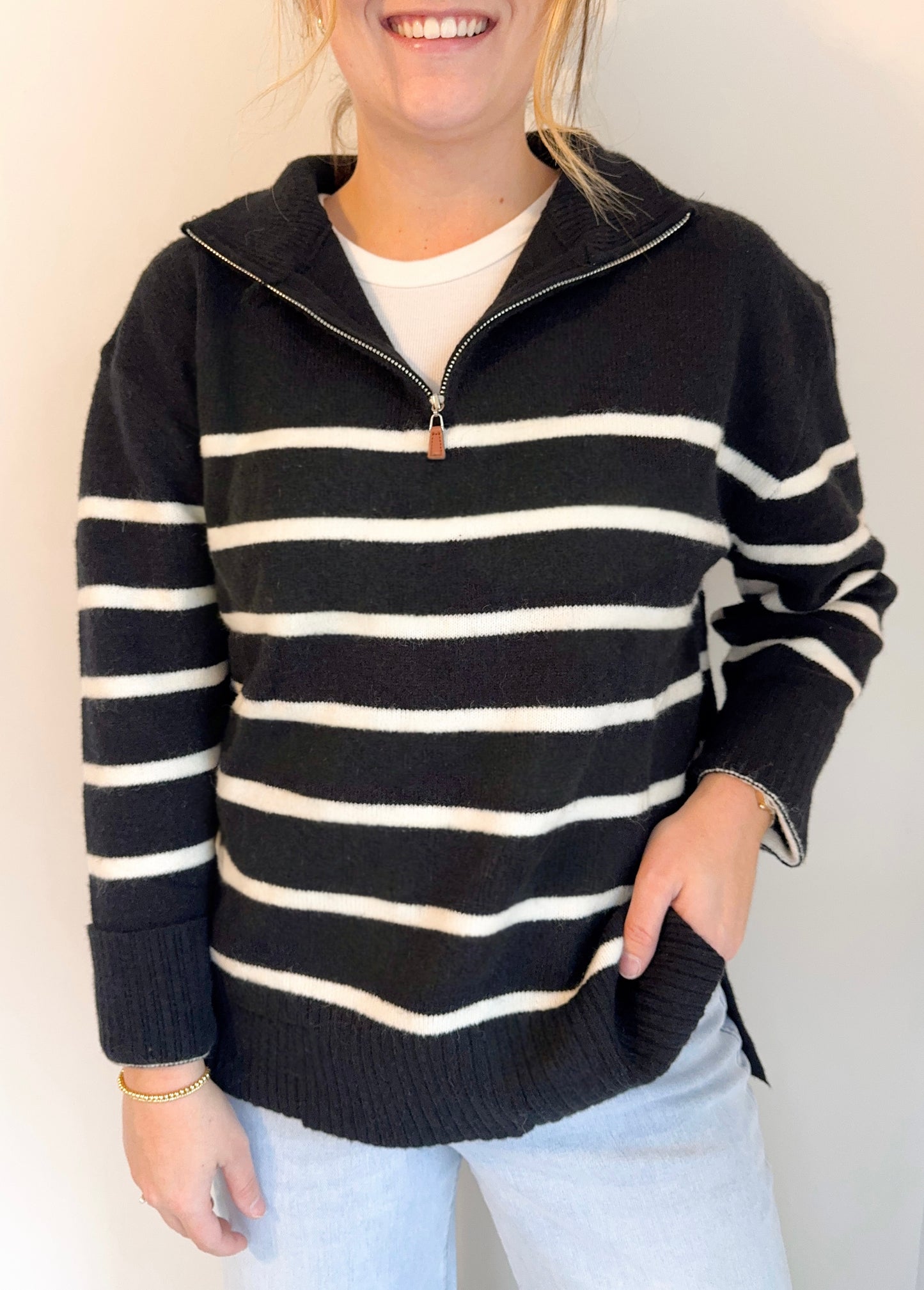Person wearing a black and white striped sweater with a plain background