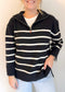 Person wearing a black and white striped sweater with a plain background