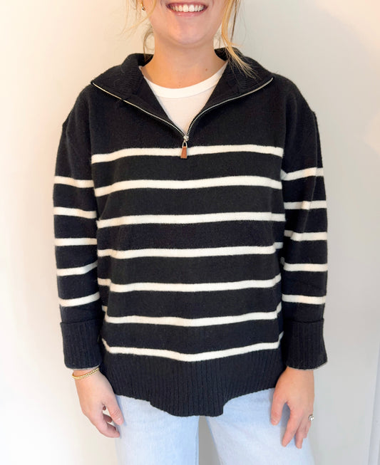 Person wearing a black and white striped sweater with a plain background