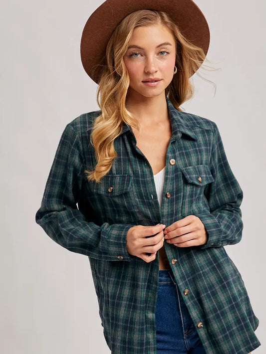 Woman wearing a plaid shirt and brown hat on a plain background